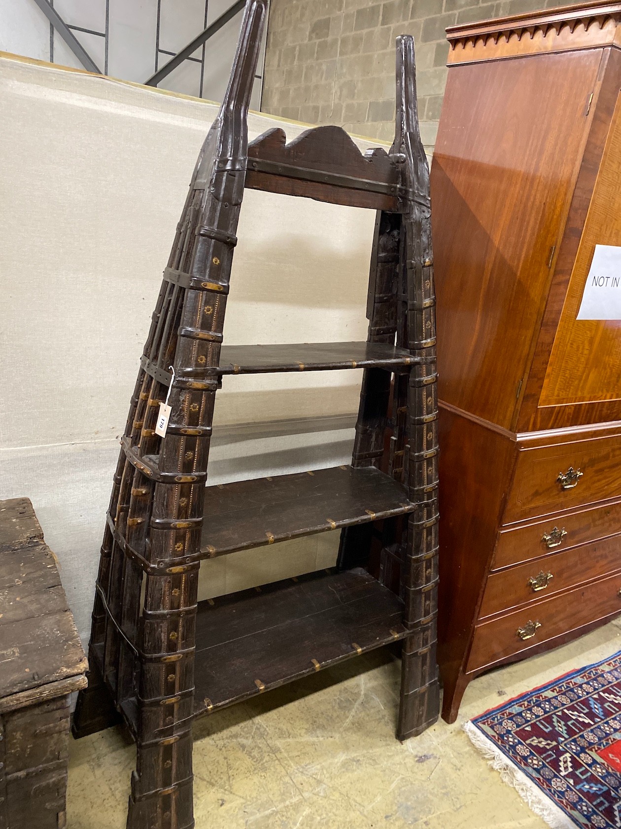 An Indian brass mounted carved hardwood three tier shelf unit, constructed from a 19th century ox harness, length 106cm, depth 40cm, height 202cm